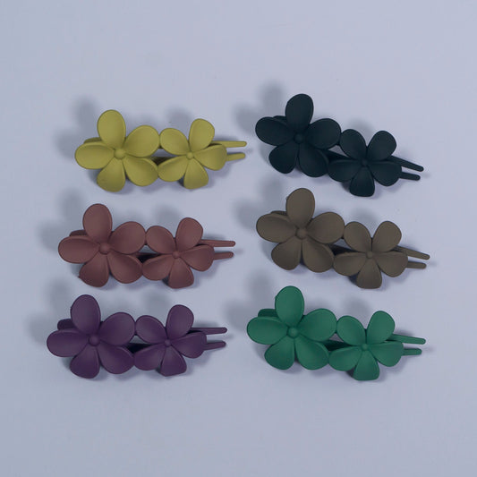 Set of six floral hair clips in different colors on a light gray background